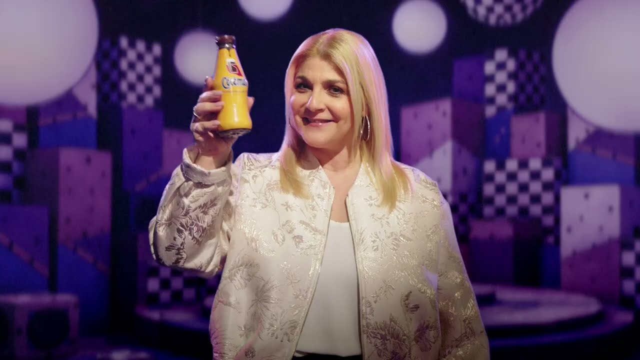 A singer raises a bottle of Chocomel in a purple set