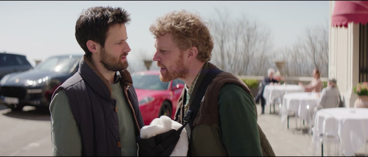 Two men argue next to a red car, from The Dadchelor
