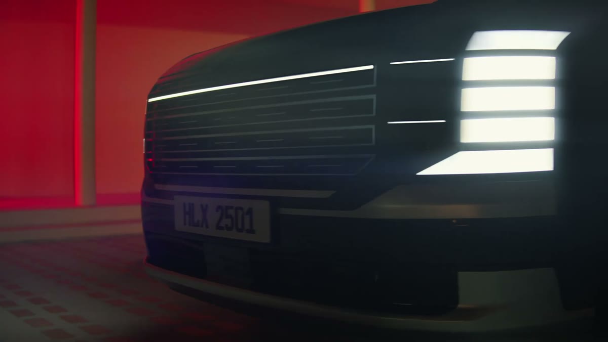 The lit grille of the Hyundai Palisade against a red wall